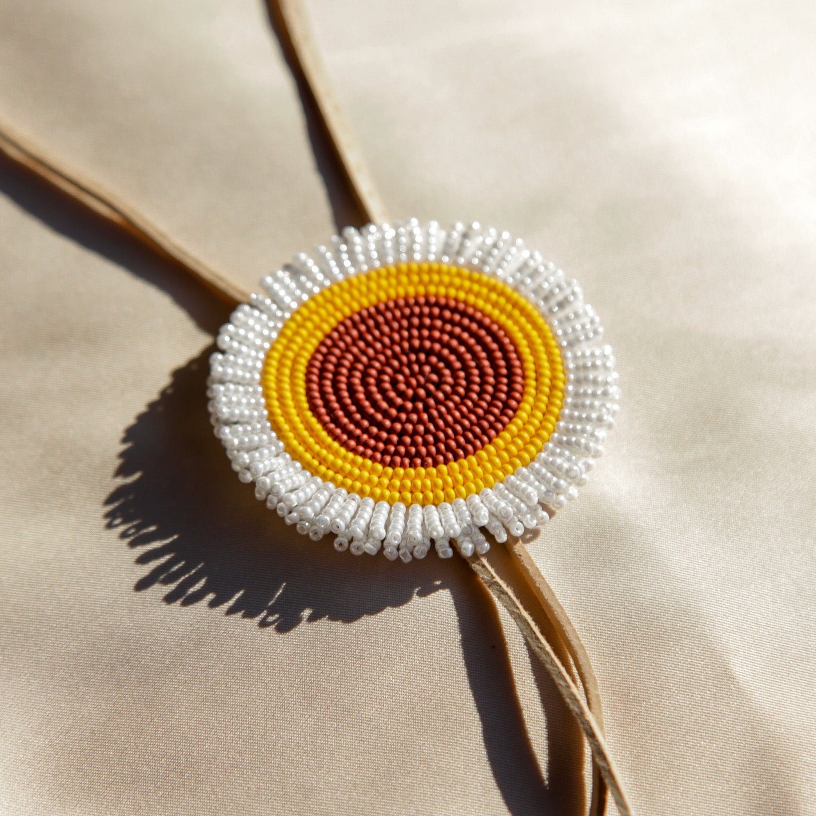 Beaded brooch with a circular design on a beige background